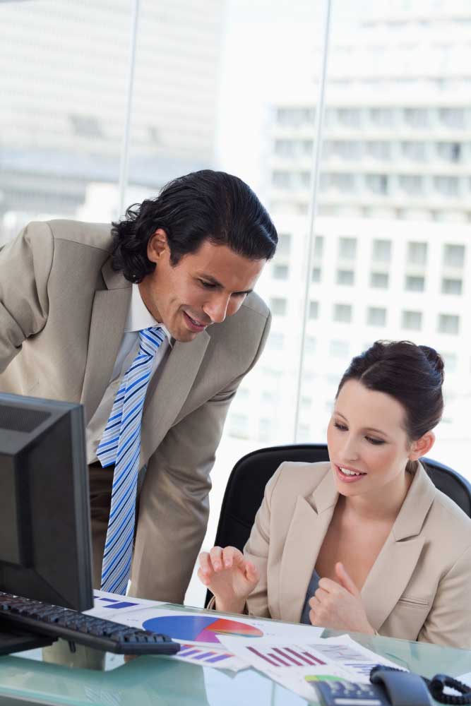 Business professionals reviewing financial charts on a computer in an office, delivering accurate bookkeeping services Fort Lauderdale for companies