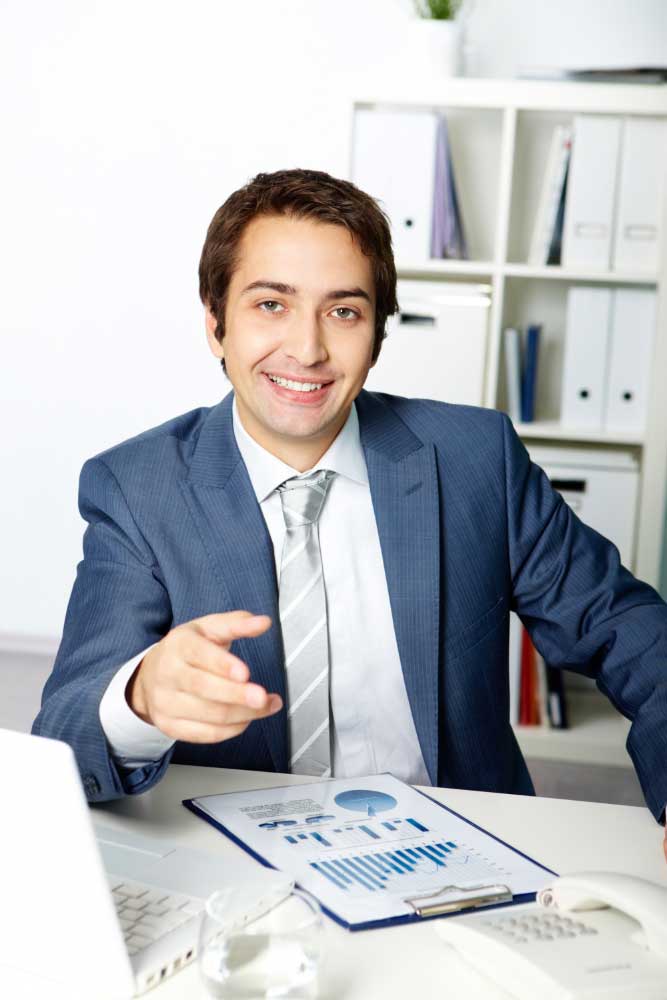 Smiling professional financial advisor at an office desk reviewing charts, representing trusted business financial consultant Fort Lauderdale services