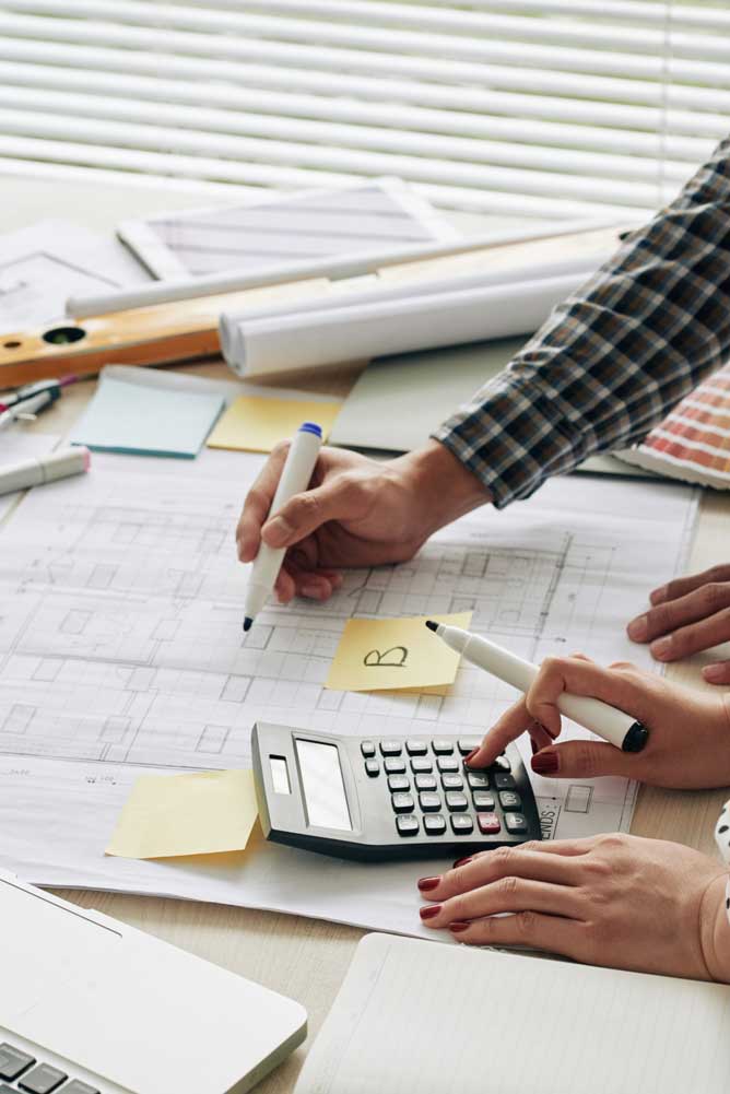 Professionals calculating costs and reviewing plans with calculator and drawings as part of miami tax planning process